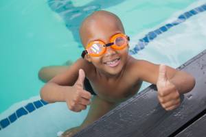 Happy child in a pool giving the thumbs up signal